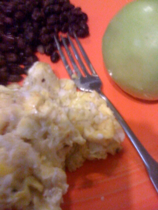 a plate with meat, beans and an apple next to a fork