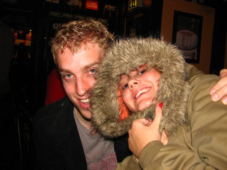 a man and woman emcing each other with a furry hood on