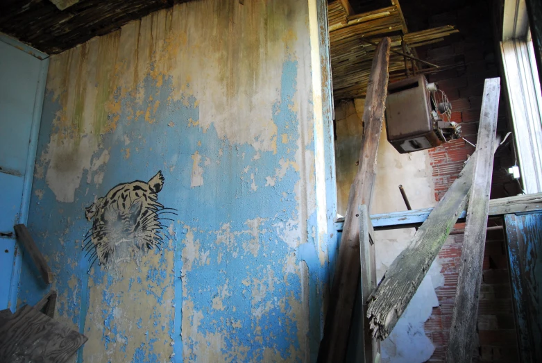 an old building with walls painted blue and chipped off with graffiti