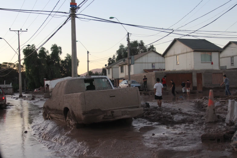 several people standing around parked cars and in the street