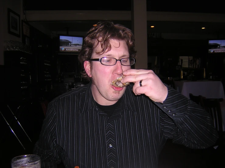 a man in glasses is taking a bite of food