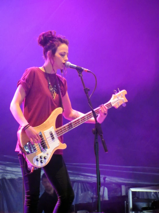 a woman standing on a stage holding a guitar