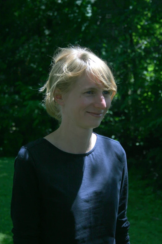 young woman standing next to a lush green forest