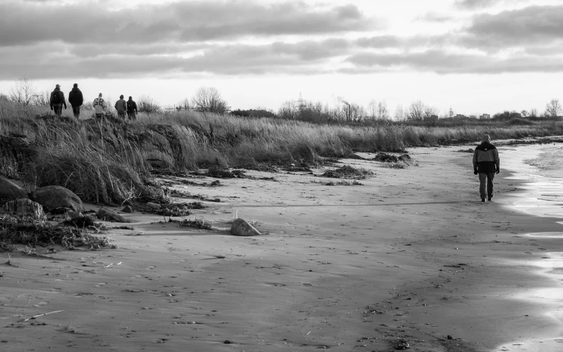 people walking down the beach in the sand