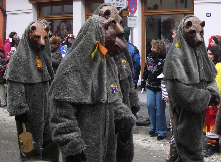 people wearing animal heads wearing robes walking down a city street