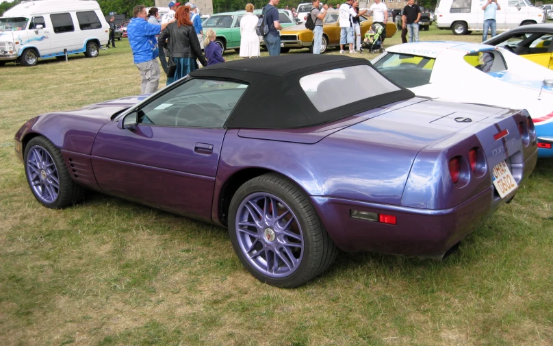 a purple sports car sits on display on the grass