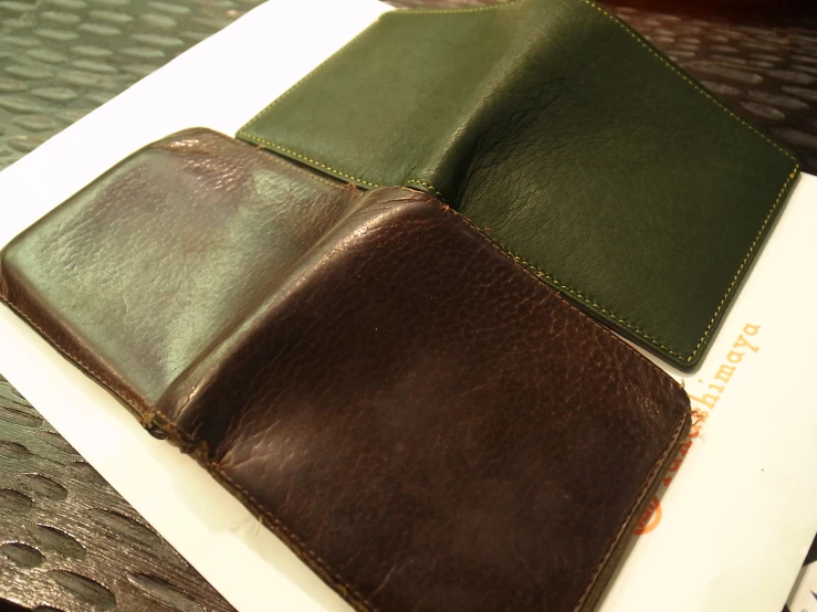 three different colors leather purses one brown, the other green
