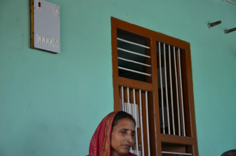 a woman sitting in front of a window while holding a phone