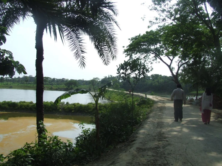 a woman and a man walk along the path to the lake