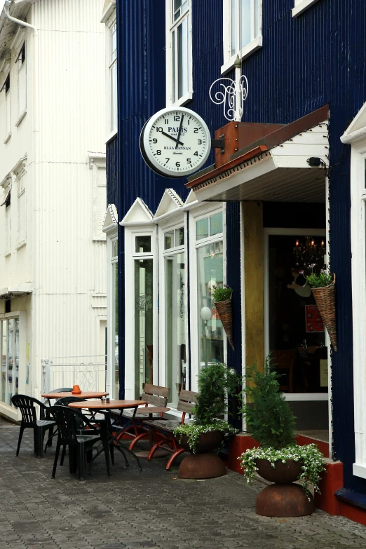 a street scene with people walking past an outdoor cafe and clock