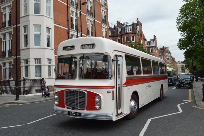 an old fashioned bus is driving down a busy street