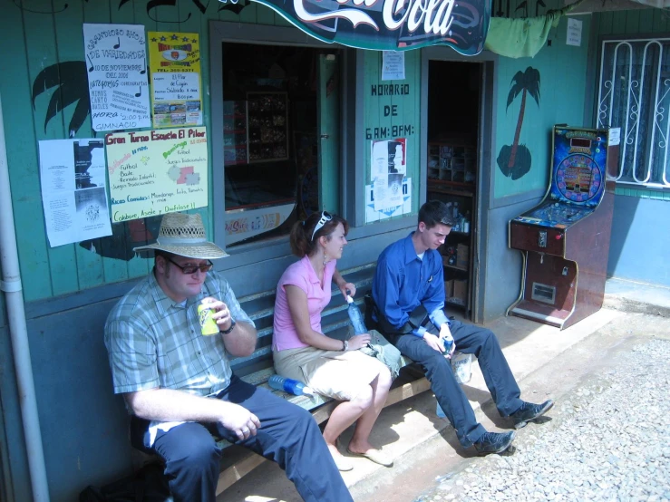 the man in a hat is sitting next to two women while sitting on a bench