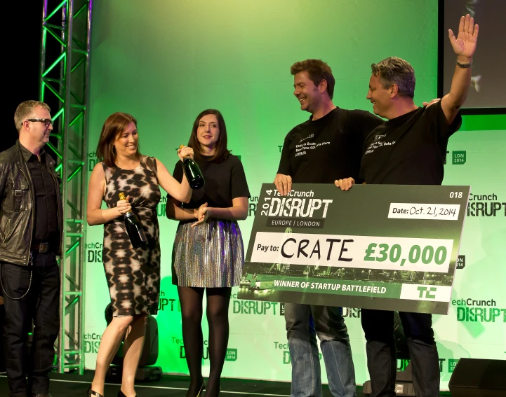 four people standing on stage while the man is giving a speech