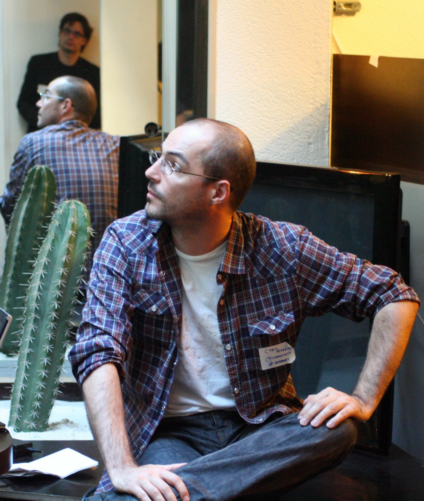 a man sitting on a couch next to a cactus