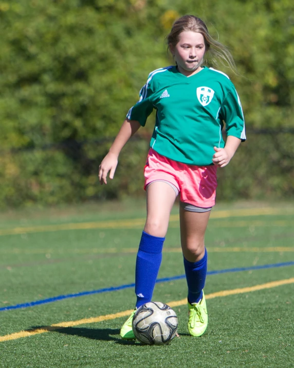 a little girl in a green shirt and a soccer ball