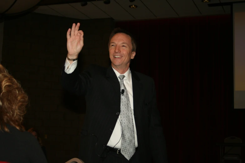 a man in suit and tie waving with a woman