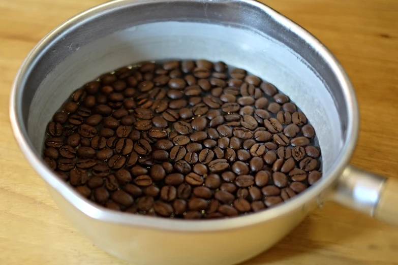 some coffee beans are in a cup on a wooden table