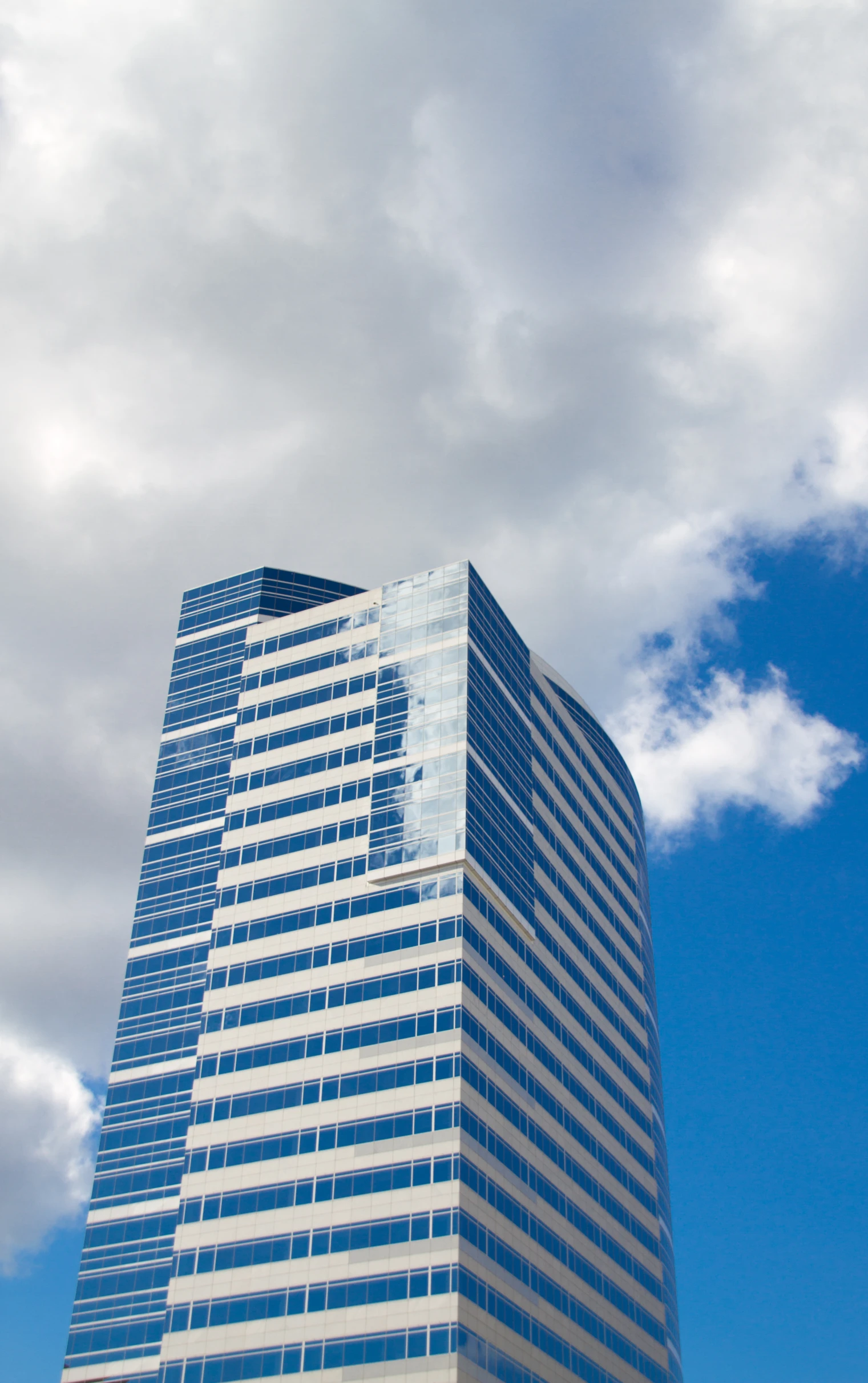 a tall glass building sitting next to a blue sky