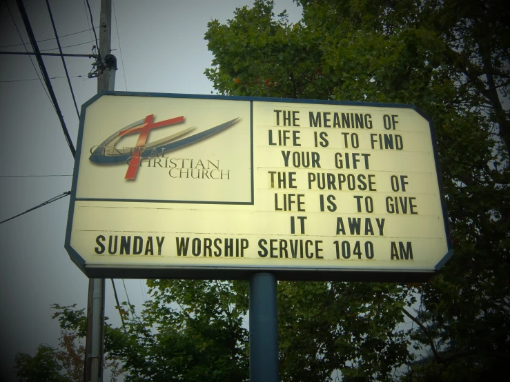 a sign in front of some trees on a cloudy day