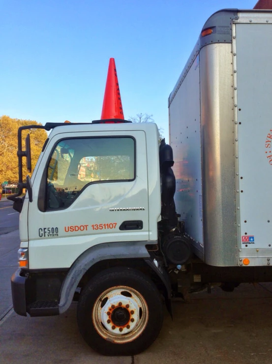 a white truck with a traffic cone on the side