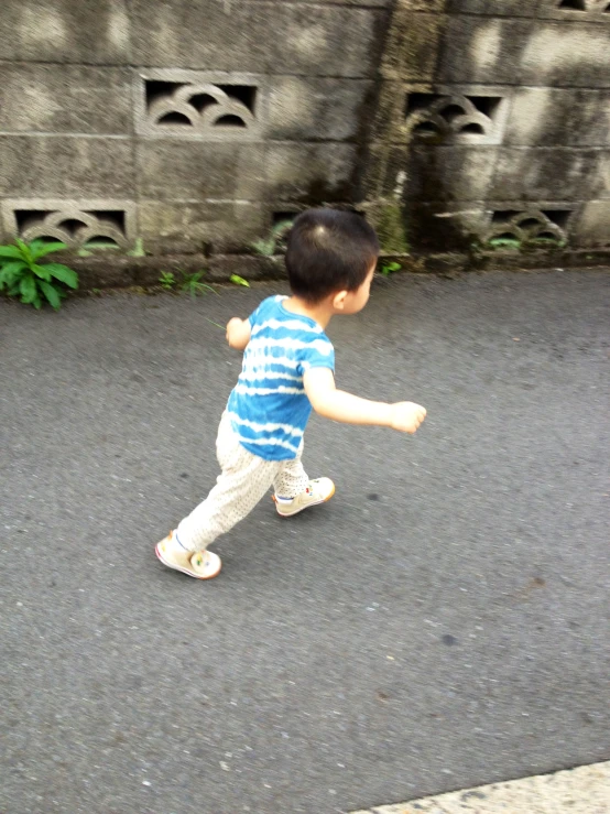 a boy in striped shirt and white pants playing with a skateboard