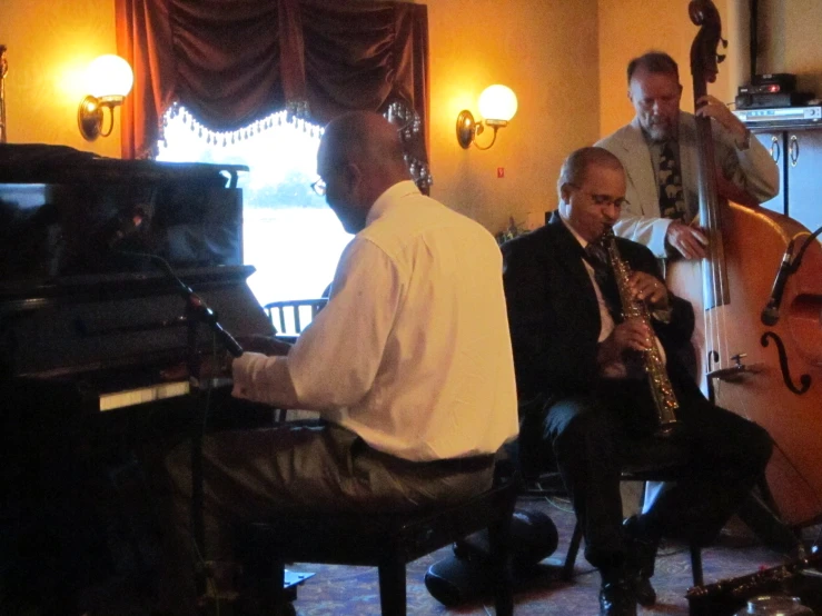 a group of men that are sitting around a piano