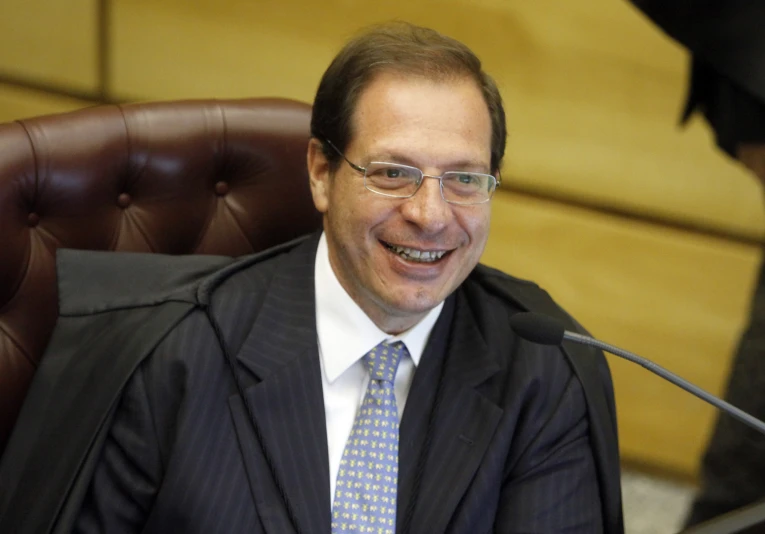 a man with glasses and a suit smiling