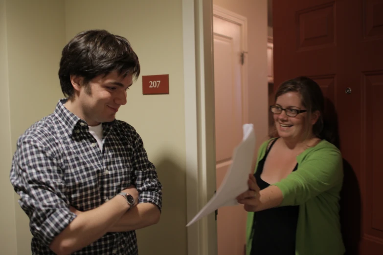 the man and woman are laughing while looking at a sheet of paper