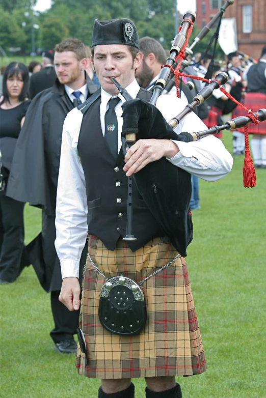 a man standing in the grass with his pipes