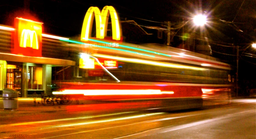 a fast moving metro train at night near mcdonald's