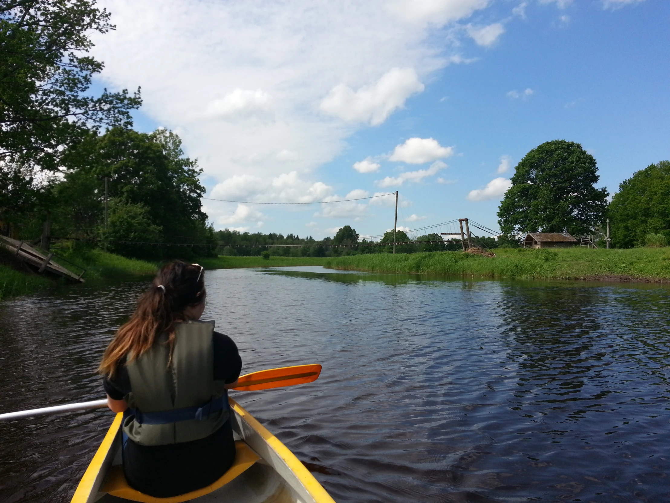 person paddling kayak down the water with trees around