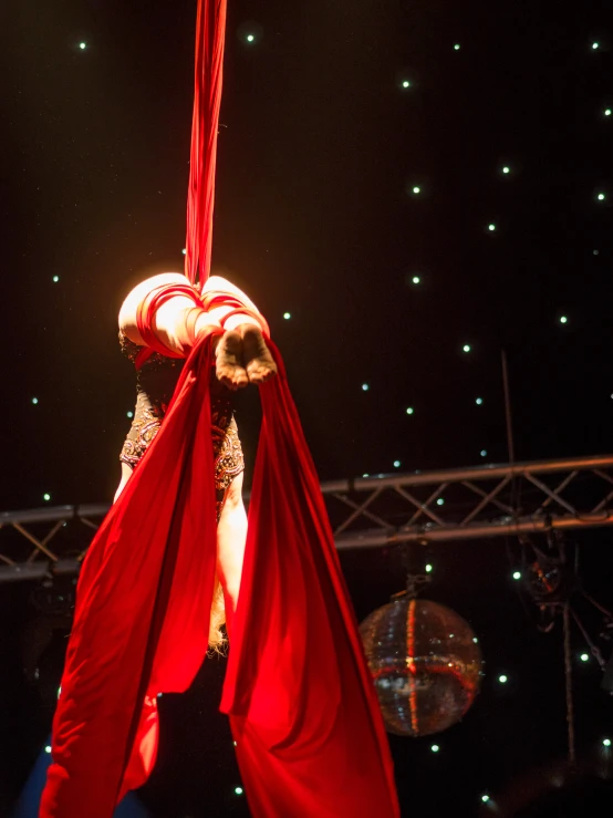 woman in costume hanging on rope while wearing large red scarf