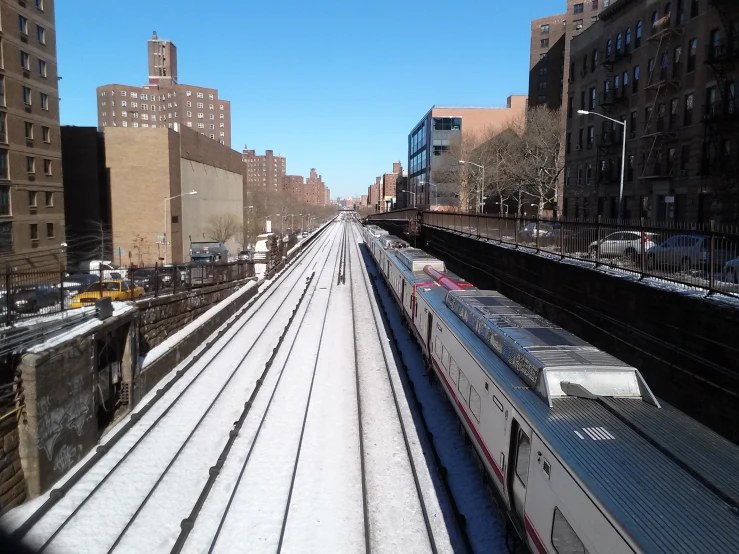 a long commuter train is passing along a city street