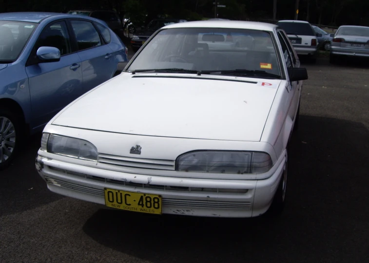 the front of an old white car, with other cars behind it