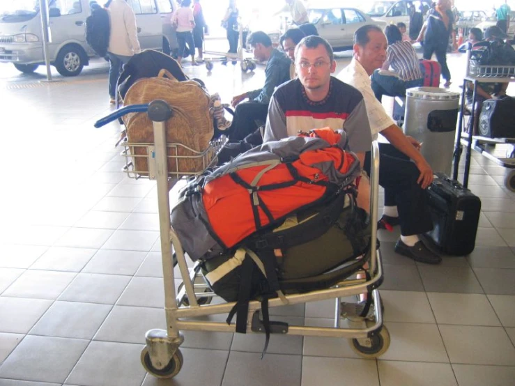 men with luggage hing a dolly in the middle of an airport