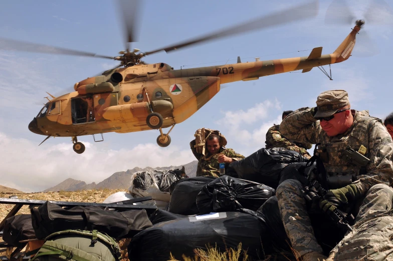 two military personnel prepare to board a helicopter