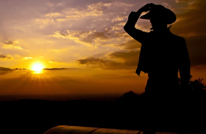 a man holding his hand up as the sun goes down