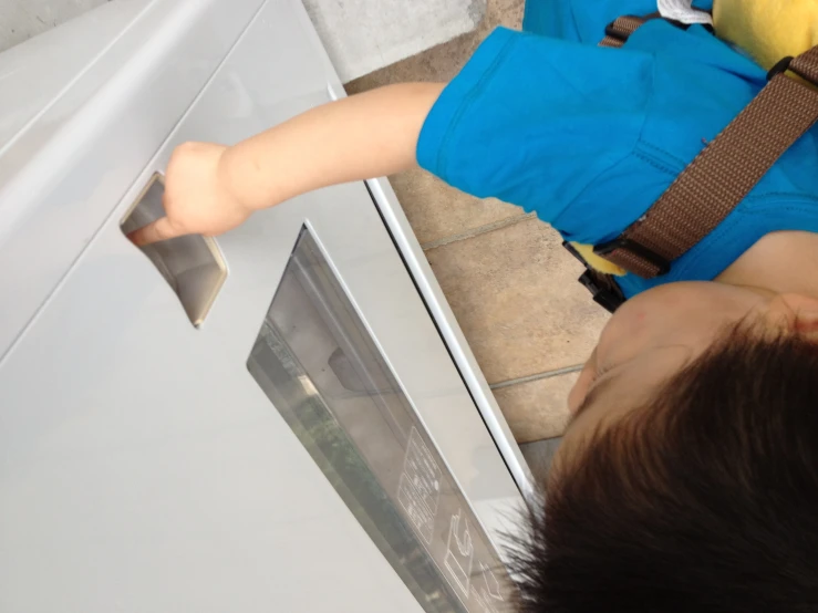 a small boy trying to open a white refrigerator