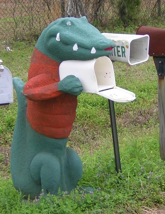 a dinosaur mailbox with its mouth open holding a sign