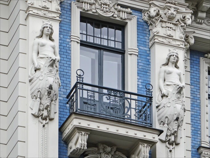 two statues of mermaids and women hang from the balconies on an apartment building