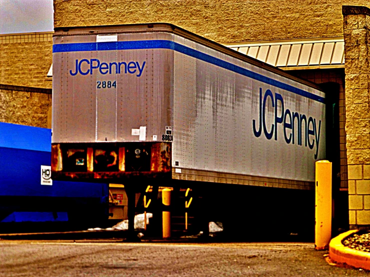 the large box truck is parked beside a brick building