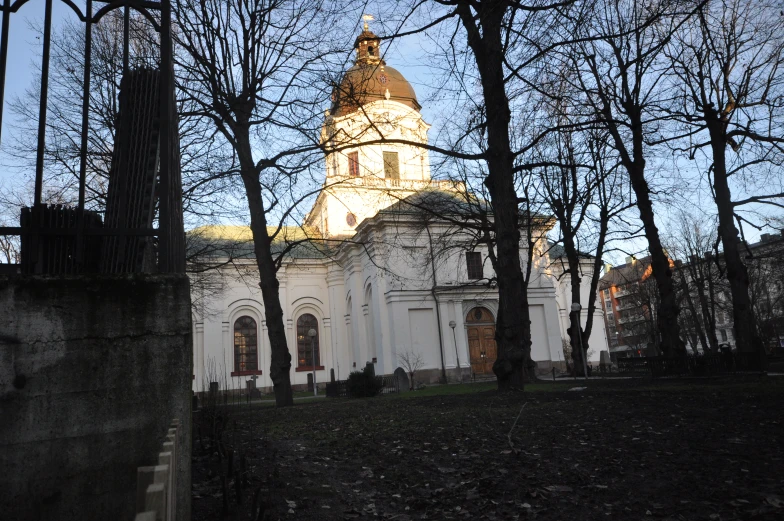 a church with a clock tower sits behind the trees