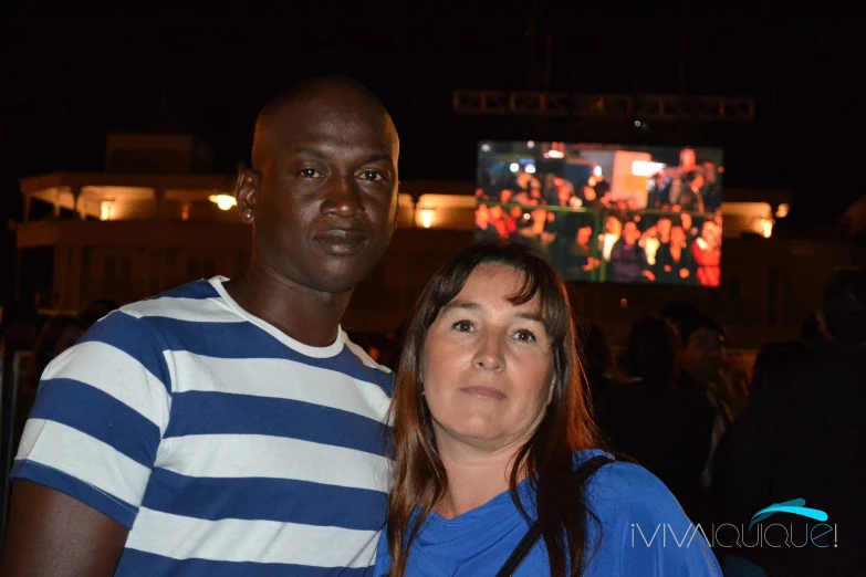 a couple standing together in front of a large screen