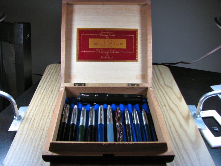several pens in their wooden box on the table