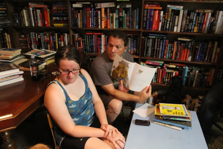 a man and woman reading in front of a book shelf