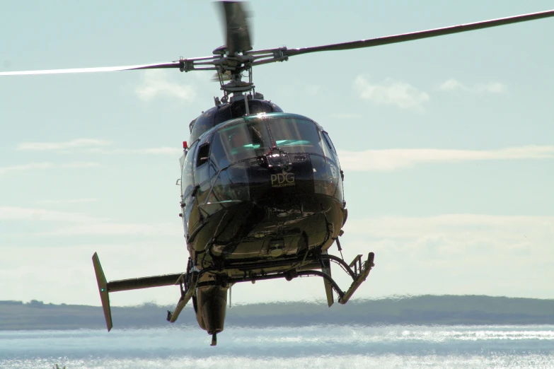 helicopter flying in the air near a body of water