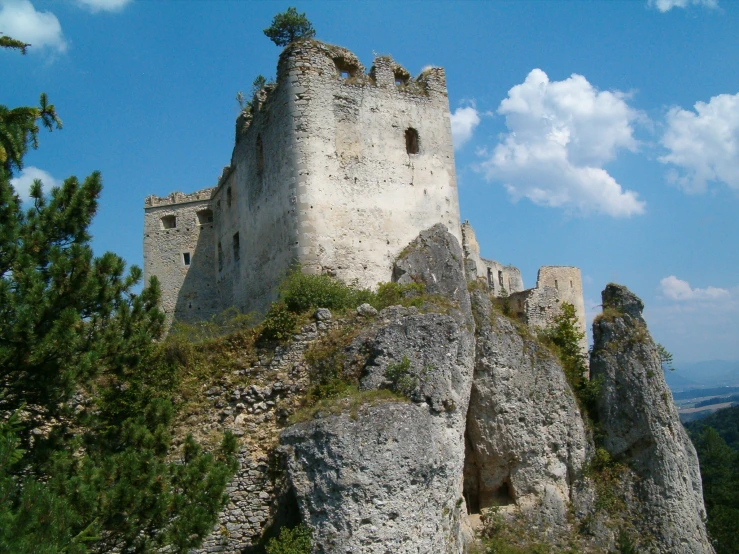 a stone building on the side of a mountain with trees