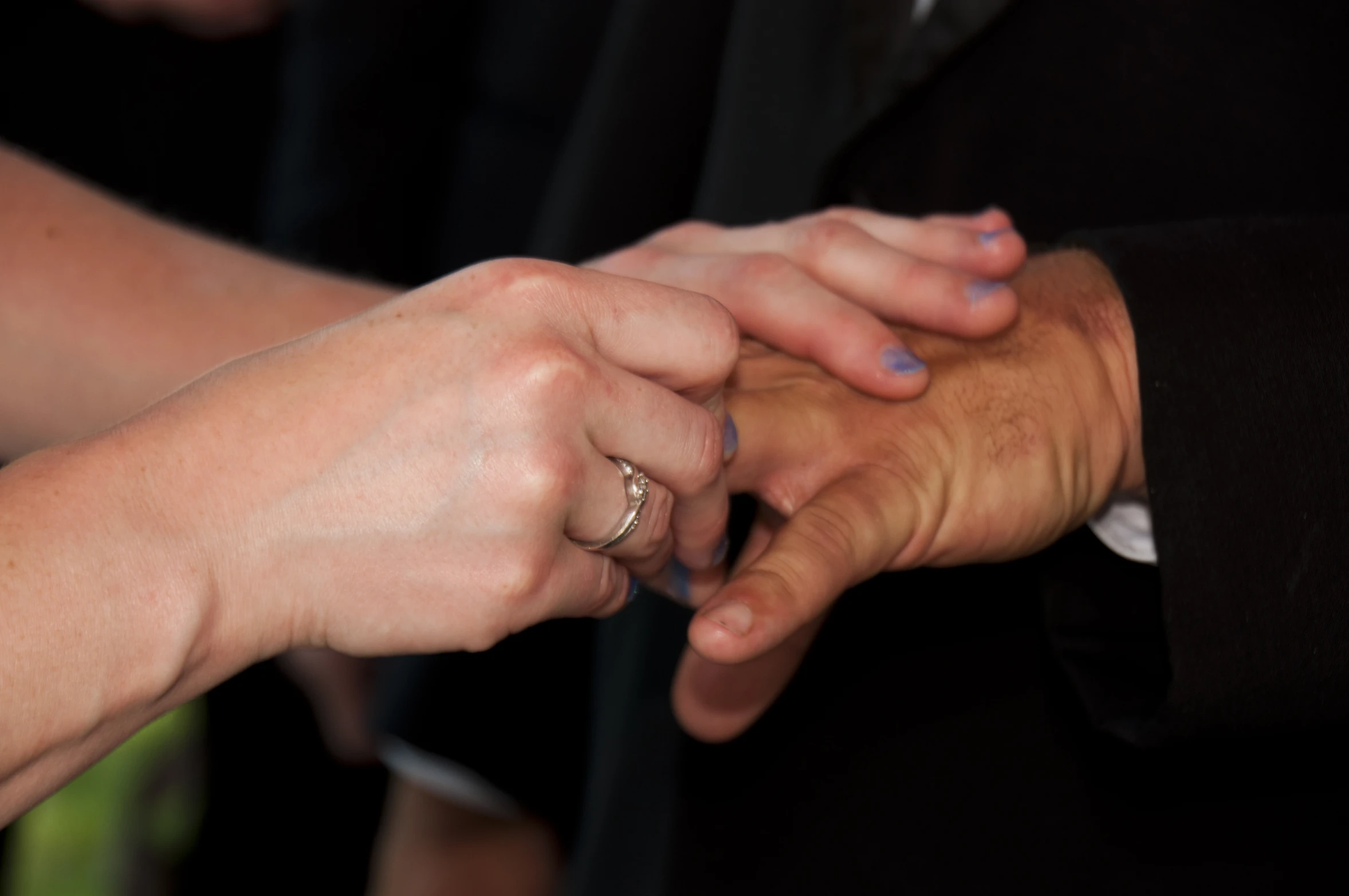 couple's hands are reaching each other over their wedding ring