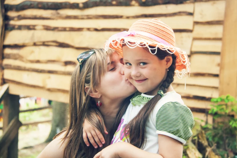 two girls are kissing each other with a straw hat