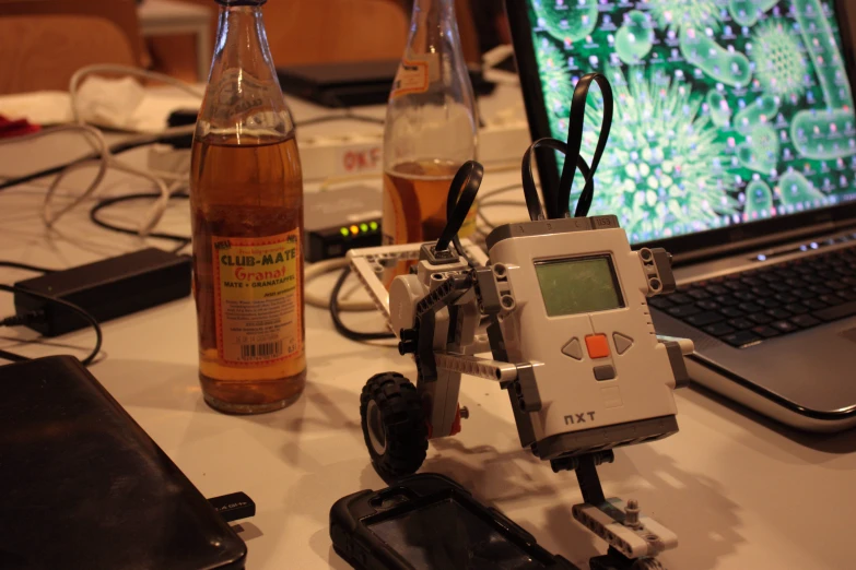 a computer sitting on a table near bottles of alcohol